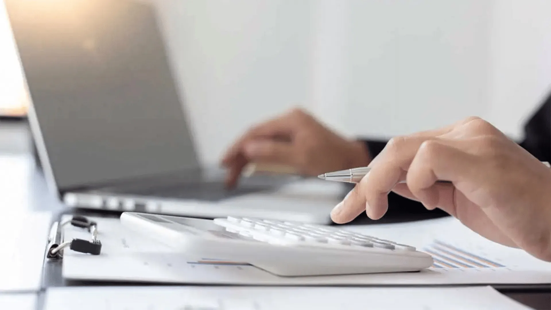An accounting professional working with a calculator and laptop